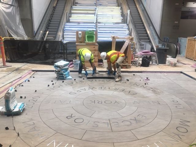 BAC Local 7 NY/NJ Tile Mechanic Bruno Zappavigna, left, and Tile Apprentice Jason Dilthey, install the signed piece of tile.